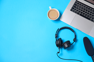 Laptop, headphones and mic with coffee, on blue table