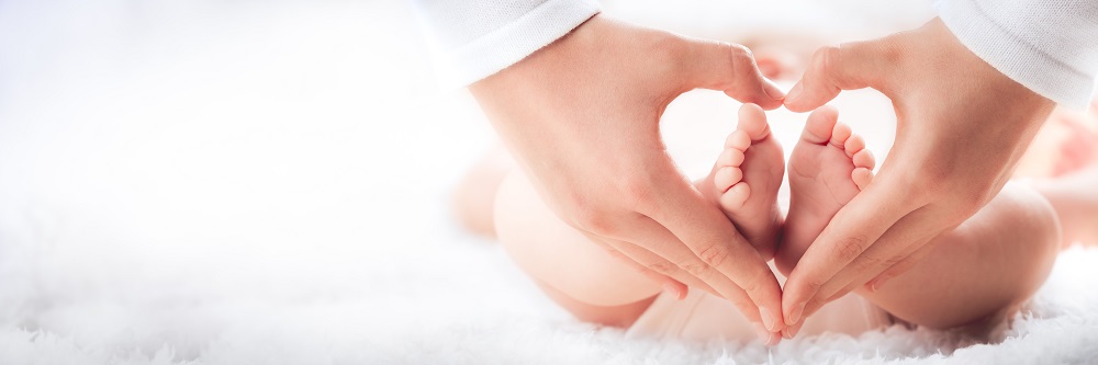 hands forming the shape of a heart surrounding a baby's feet