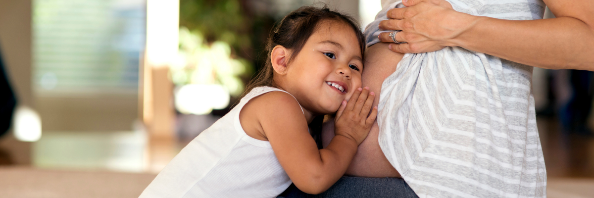 child snuggling pregnant belly