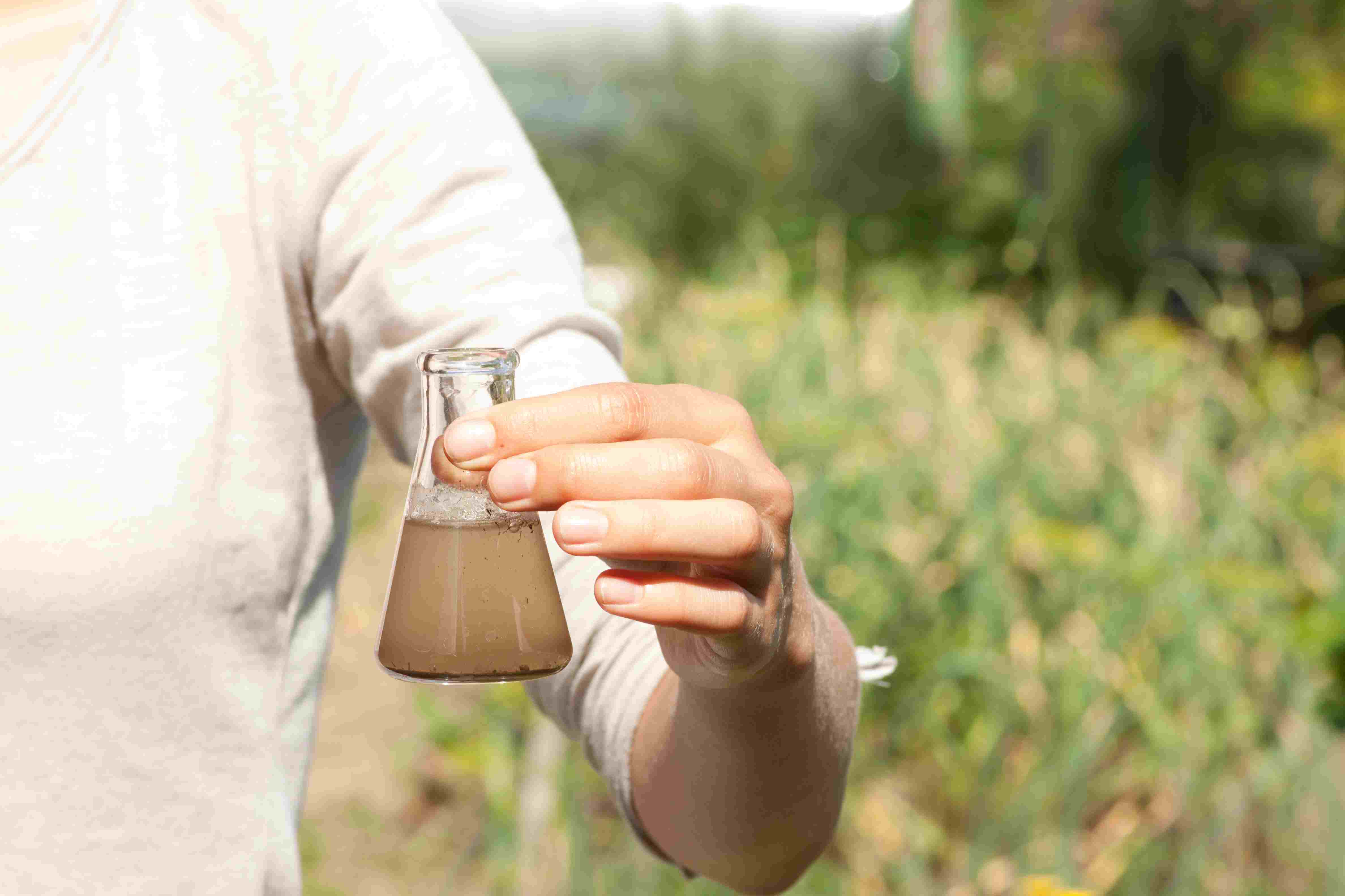 Person holding glass bottle with brown water