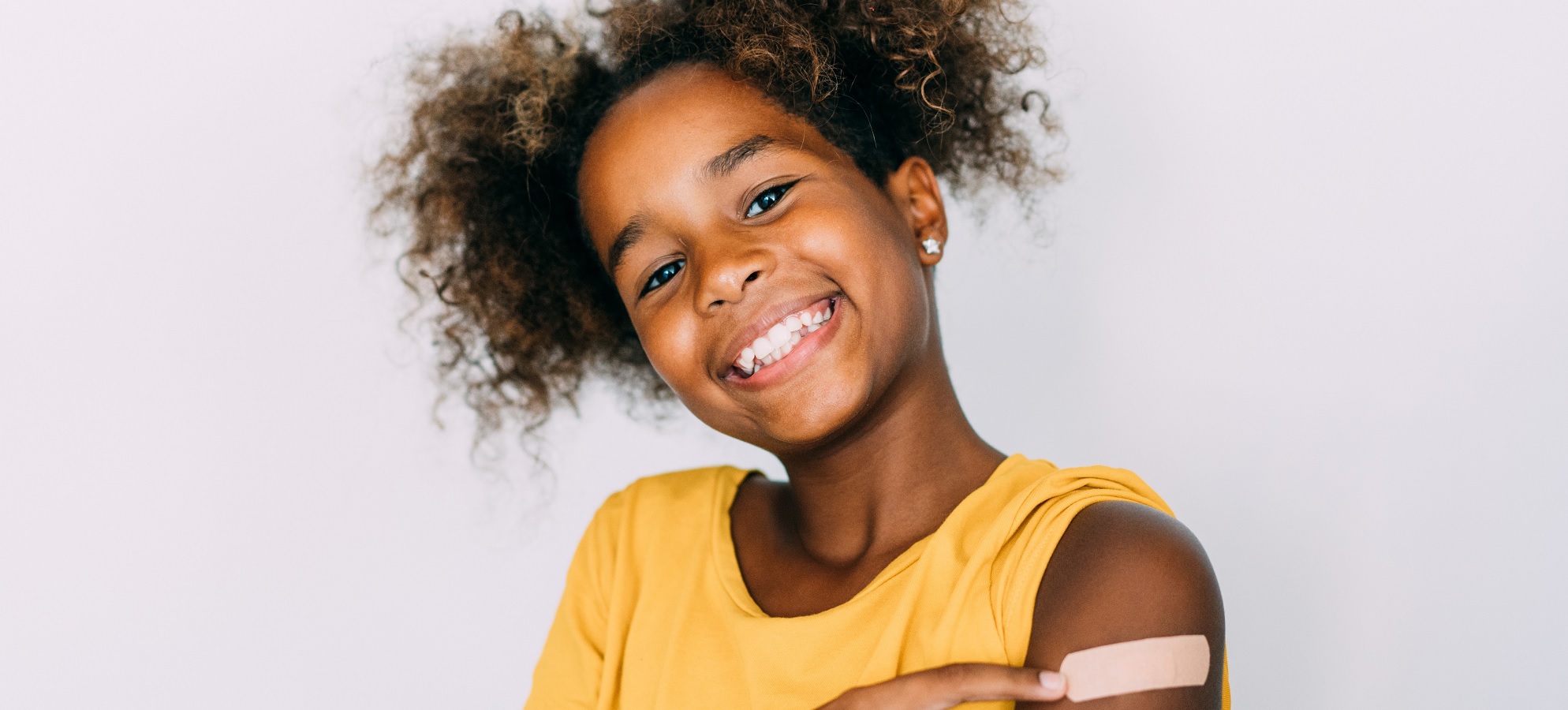 smiling girl pointing to band-aid on shoulder