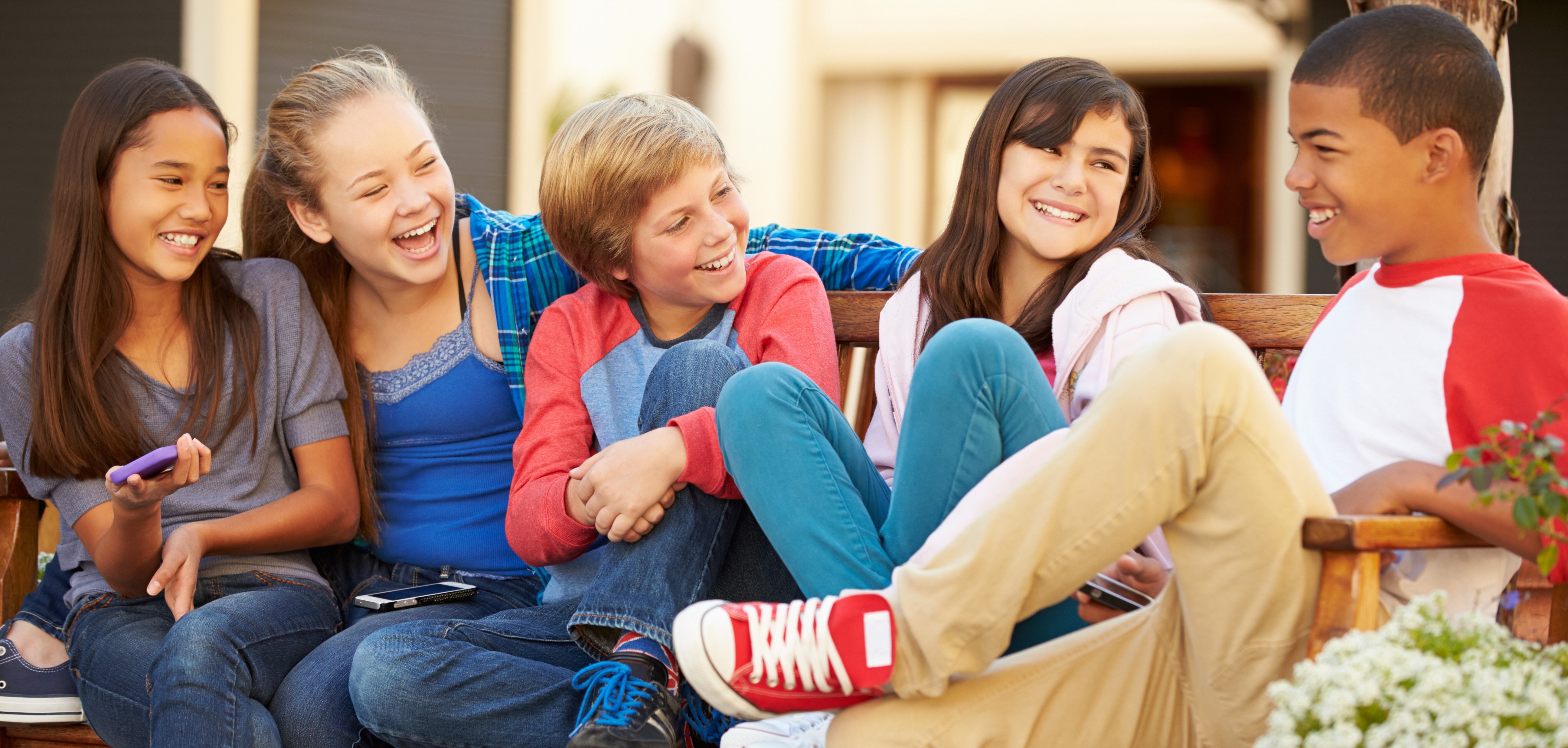 a group of smiling older kids sitting on a bench