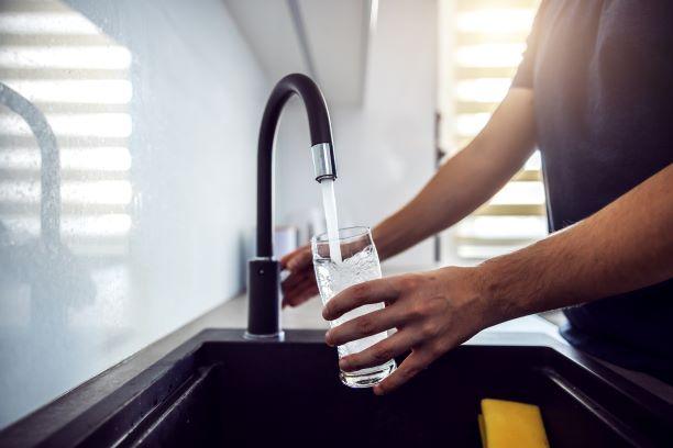 Person filling a glass of water at the kitchen sink