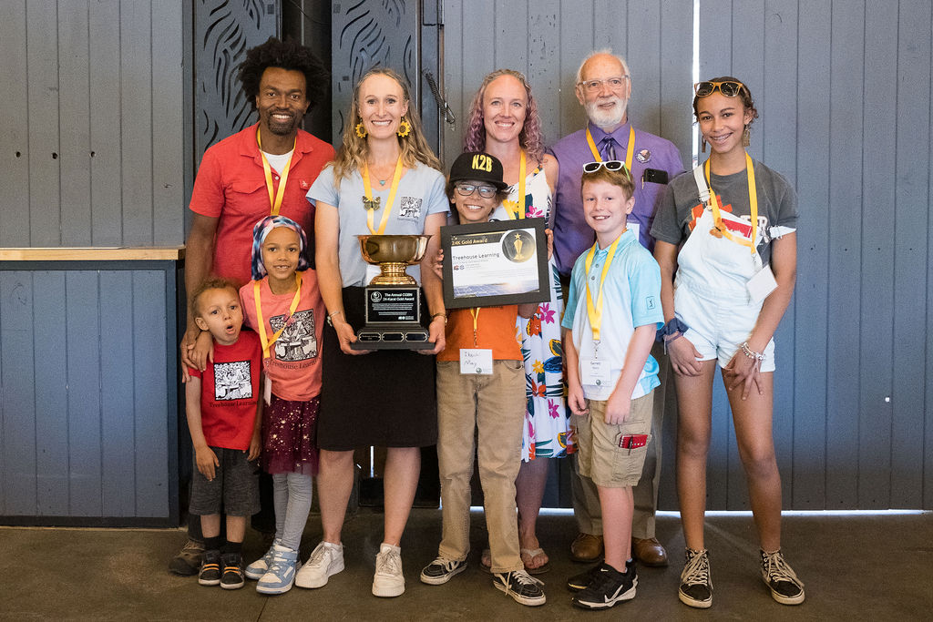 Four adults and five children from Treehouse Learning holding the 24-karat Gold award winner trophy and plaque