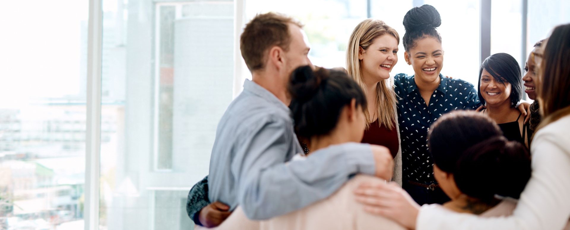 Coworkers in a huddle smiling and laughing.