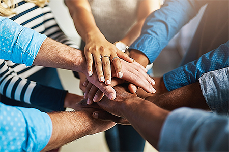 a group of people stack their hands on top of each other's hands in solidarity