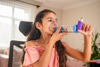 A young girl uses a spacer inhaler