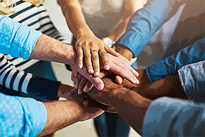 a group of people stack their hands on top of each other's hands in unity