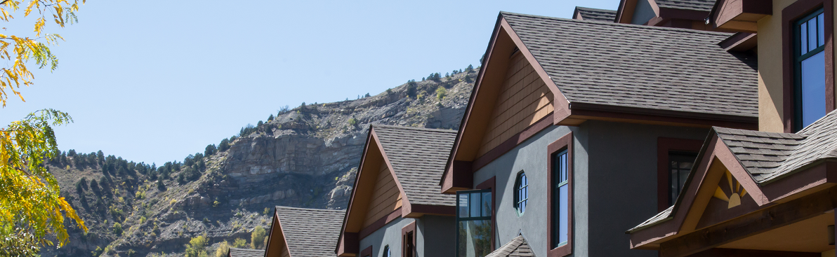 A row of house roofs with mountains and sky behind them.