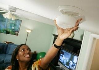 Woman installing a smoke detector in her home.