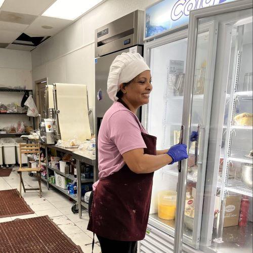 A Hira Cafe & Patisserie employee is seen opening the door to a refrigerator that is equipped with Energy Star options