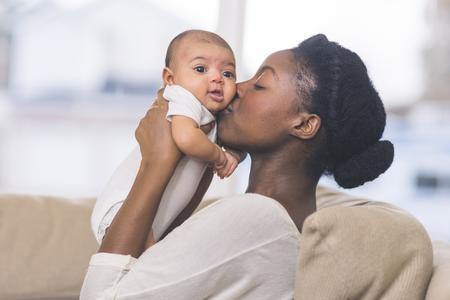 mother holding baby with her face pressed against it